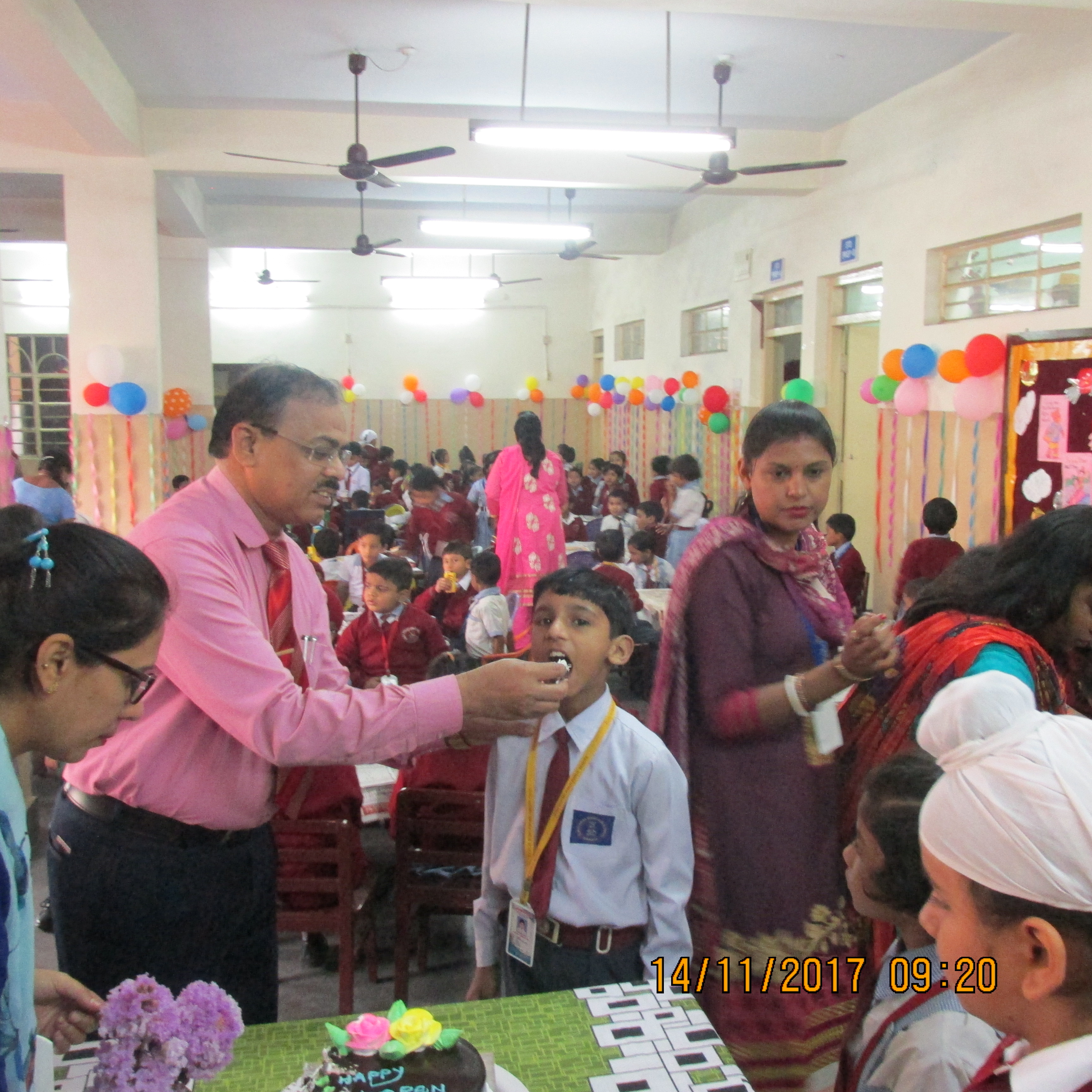 Principal Sir feeding the cake to children